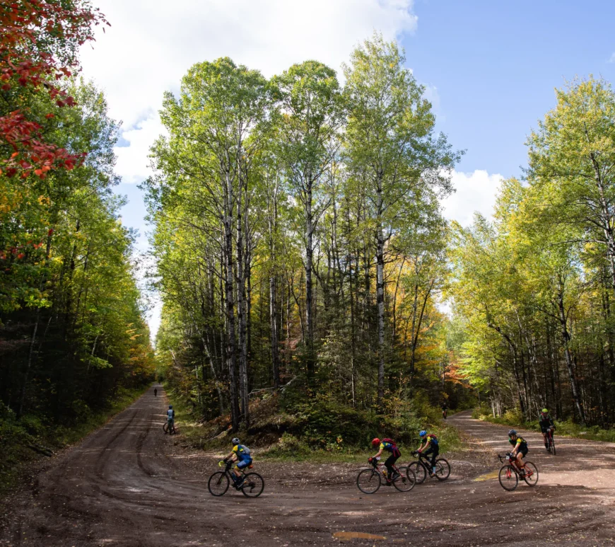 Cyclists riding around a smooth curve on a climb in northern Minnesota. The event is called Heck of the North.
