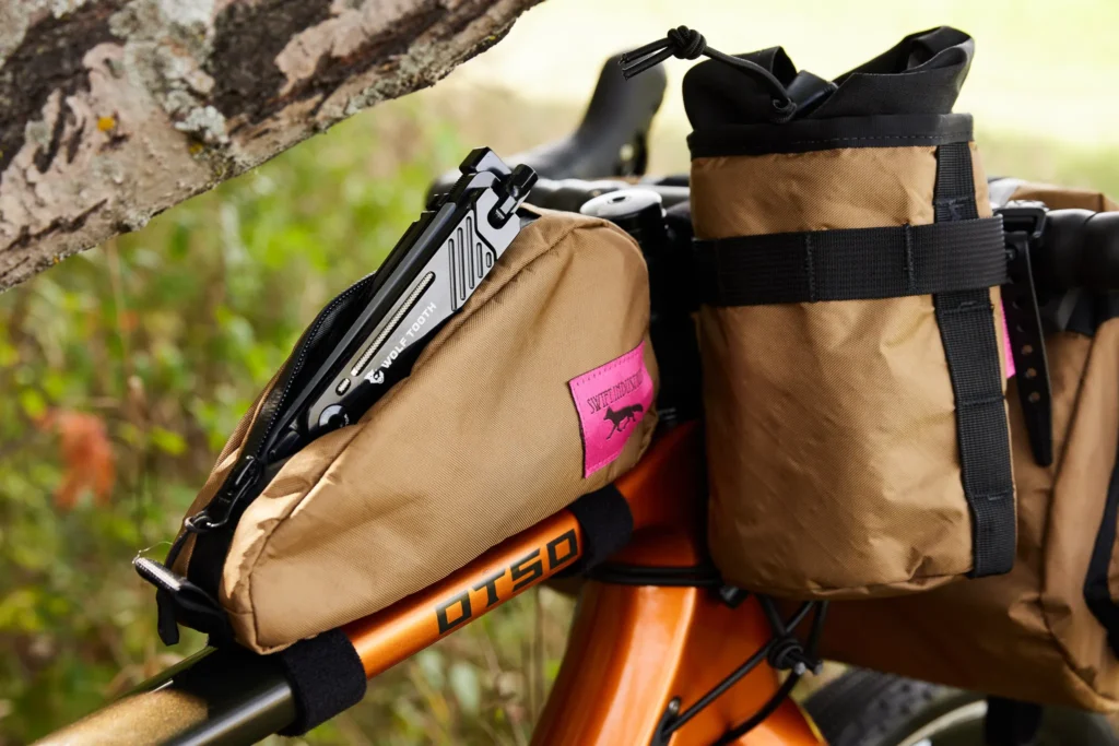A Swift Industries Feed bag and top tube bag are positioned on an Otso Cycles Waheela C. A Wolf Tooth 8-Bit Kit One is poking out from inside of the top tube bag.