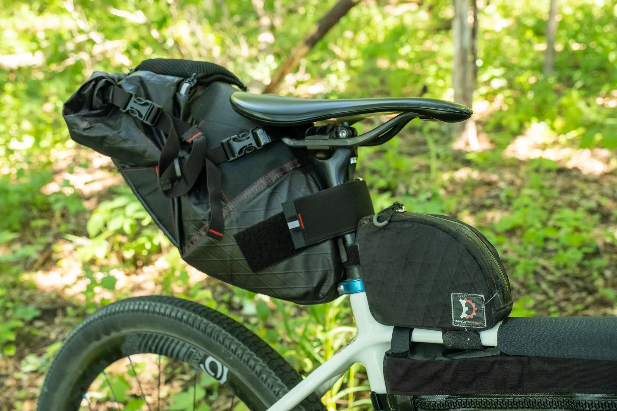 A Waheela C with a full bikepacking setup in a lush forest. The bike has a seat bag, a top tube bag, and a frame bag.